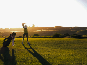 Golfer teeing off at sunset